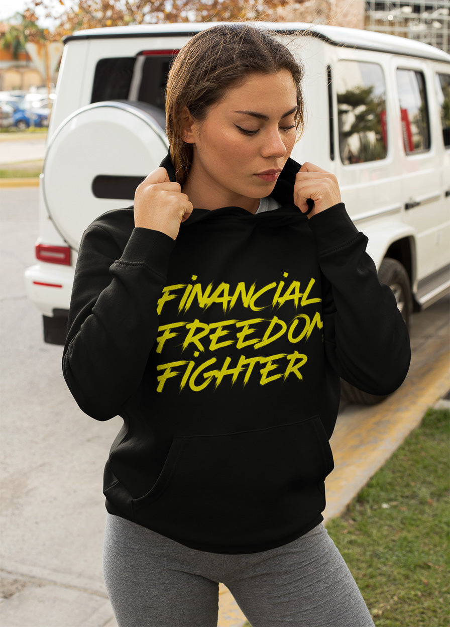 a woman showing the frontside of a black colored hoodie from the brand Stanley Stella with the inscription "Financial Freedom Fighter" in large yellow letters